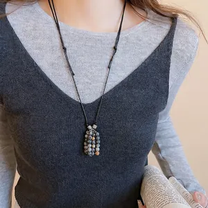 Vintage stone beaded pendant necklace with adjustable black cord on a model