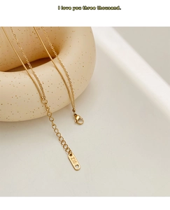 Macro detail of 18K gold-plated double-layer necklace with lobster clasp and logo tag
