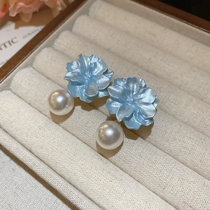 Macro shot of blue resin flower earrings with white pearl pendants in a velvet box
