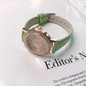 Detail of rose gold quartz watch with diamond bezel and light green leather strap