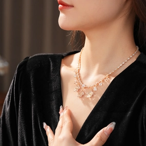 Close-up of elegant gold flower necklace with teardrop pendant on female neck