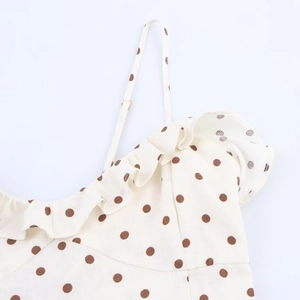 Detailed close-up of white polka dot midi dress showing ruffle trim and adjustable straps