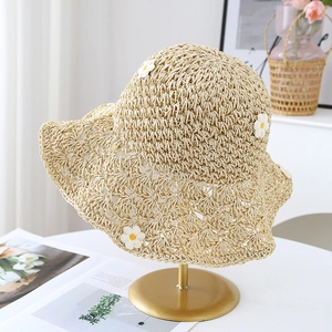 Détail de chapeau de paille orné de petites marguerites blanches et bordure ondulée