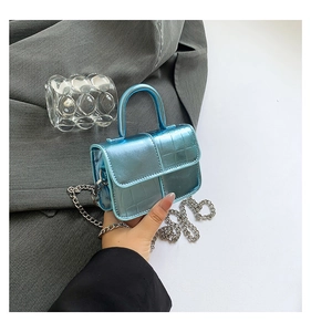 Detailed view of mini blue patent leather bag with crocodile texture and silver chain strap