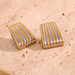 Vue macro des boucles d'oreilles trapèze bicolores avec texture rayée verticale or et argent