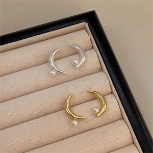 Macro shot of gold and silver moon pearl stud earrings in a beige velvet jewelry box