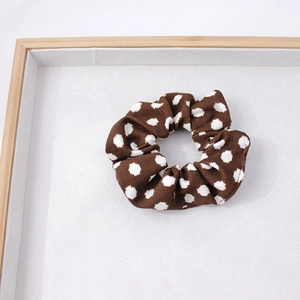 Vue détaillée du chouchou en tissu à pois marron sur un plateau d'exposition blanc