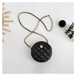 Macro detail of black quilted mini round bag with gold flower clasp and chain strap