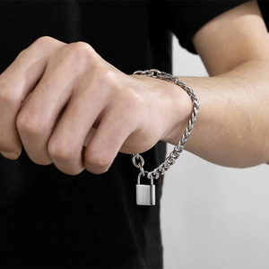 Nahaufnahme eines silbernen Panzerarmbandes im Punk-Stil mit Vorhängeschloss-Anhänger