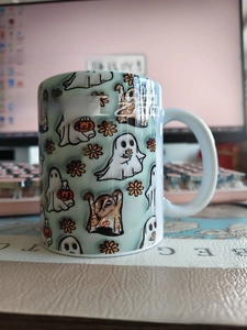 Detail of a ceramic Halloween mug featuring cute 3D ghost and pumpkin patterns