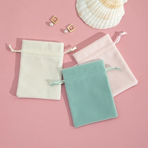Three plush drawstring jewelry pouches in white, pink, and mint green colors
