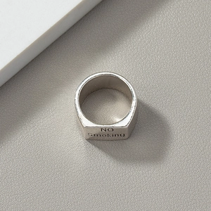 Silver signet ring with NO SMOKING engraving on textured grey leather background