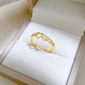 Adjustable gold heart ring with white zircon stones on a beige jewelry gift box display
