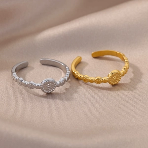 Detail of adjustable open rings with vintage hammered texture on champagne silk background