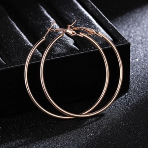 Close-up of rose gold large hoop earrings on a textured black luxury jewelry box
