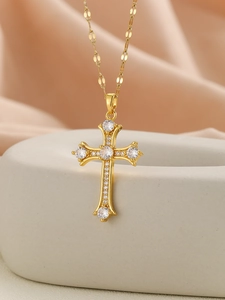 Macro shot of gold cross necklace with large white zircons on pink silk background