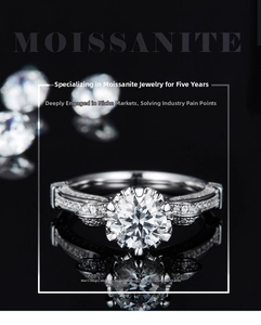 Close-up of a 1ct moissanite ring with six-prong setting on a black reflective surface