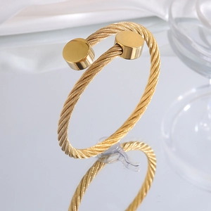 Detailed shot of gold-plated wire twisted bangle with circular flat ends on mirror