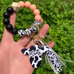 Close-up of silicone beaded bracelet with Mama cow head charm and tassel on hand