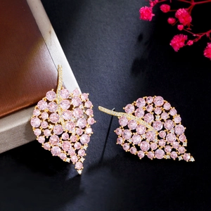 Detailed close-up of gold leaf-shaped earrings with pink round zircon inlay and fine setting