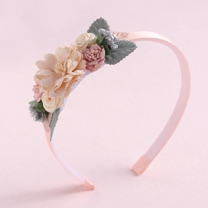 Detailed view of handmade pink floral headband with delicate fabric flowers and green leaves