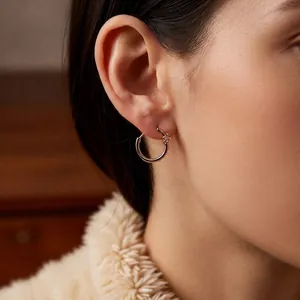 18k gold plated hoop earrings with zircon stones worn by a model in a warm setting