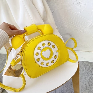Detail showing creative yellow patent leather phone bag with dial and white heart motif