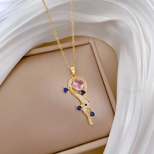 Macro detail of a gold lizard necklace pendant set with pink, blue, and clear gemstones