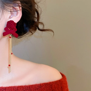 Detail of red flocked floral bow earrings with golden crystal tassels on model