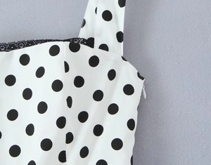 Detail of square neckline with black lace trim and side zipper on white polka dot dress