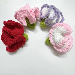 Macro view of handmade crochet flowers in red pink and purple with knit texture