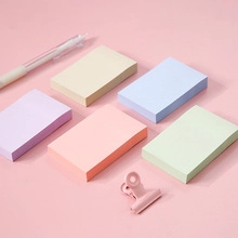Close-up of five colorful rectangular sticky note pads with a pen on pink background