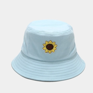 Dettaglio del ricamo a girasole e delle cuciture su un cappello a secchiello blu chiaro