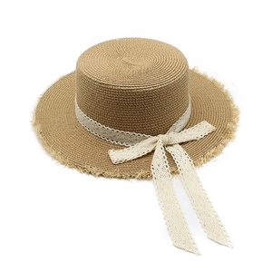 Detail of bohemian flat top straw boater hat featuring lace ribbon bow and frayed edges