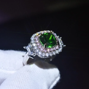 Macro detail of platinum-plated ring featuring green cushion-cut stone with halo accents