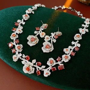 Detail of red zircon flower necklace and earrings on dark green velvet background