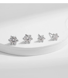 Close-up of four moissanite crown earrings in various sizes with 6-prong silver setting