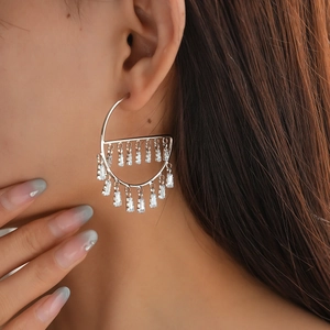 Close-up of geometric zircon tassel earrings worn by model with elegant silver needle design