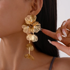 Detail of gold oversized floral tassel earrings with rhinestones on model's profile