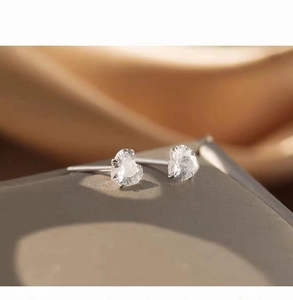 Macro shot of silver heart stud earrings featuring clear zircon and claw setting detail