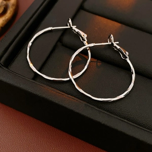Close-up of silver hoop earrings with a hammered metal texture on black leather background