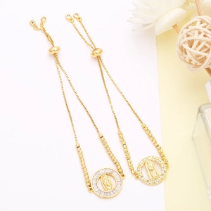 Detail of adjustable gold-plated bracelets featuring Virgin Mary pendants and cubic zirconia