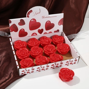 Close-up of 12 red rose shaped soap flowers in a white heart pattern gift box