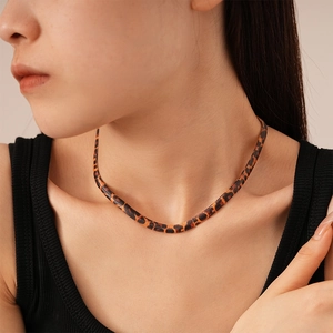 Detail shot of flat leopard print snake chain necklace worn on neck in close-up view