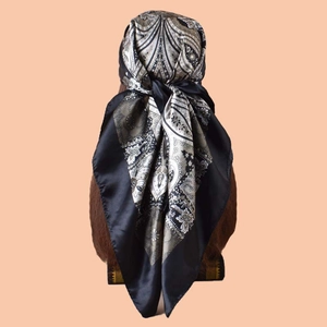 Detailed back view of a black paisley square silk scarf draped on a mannequin head
