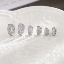 Detailed set of six cubic zirconia studded silver huggie earrings on a white tray