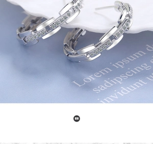 Macro detail of silver hoop earring with paved cubic zirconia on light blue textile