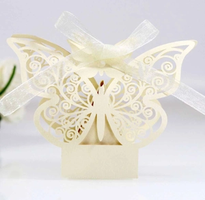 Detail of beige laser-cut butterfly candy box with intricate patterns and silk ribbon bow
