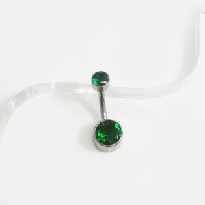 Detail of G23 titanium belly ring featuring double dark green zircon stones on white background