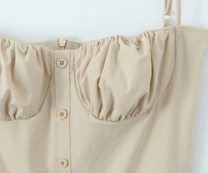 Detailaufnahme von beigefarbenem Camisole-Kleid mit plissierter Brust und Knopfdetails